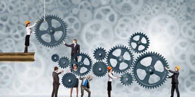 People collaborating to assemble large interconnected gears symbolizing teamwork.