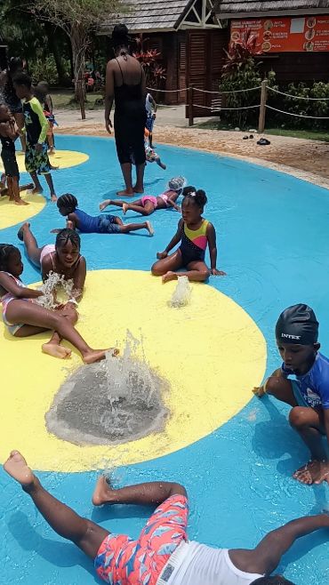 Children playing and splashing in a colorful water play area with fountains.