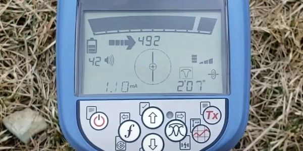 Close-up of a blue electronic measuring device on dry grass.