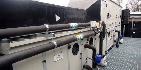Industrial HVAC system with large insulated pipes and control panels on a metal platform.