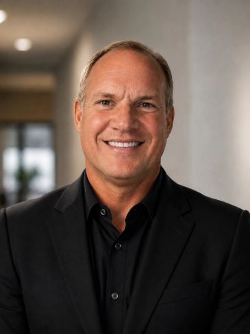 Smiling man in a black suit jacket.
