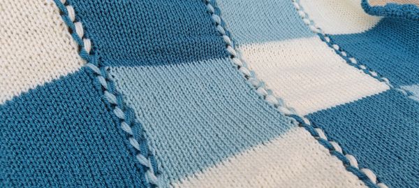 A knitted and crocheted blue checked blanket