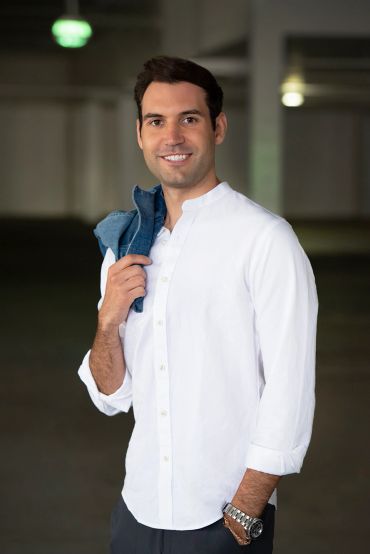 Smiling man in white shirt holding a jacket.
