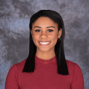 Smiling young woman with straight black hair and maroon top.