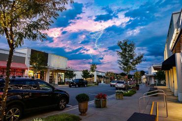 Lightning strikes in a shopping area at dusk.