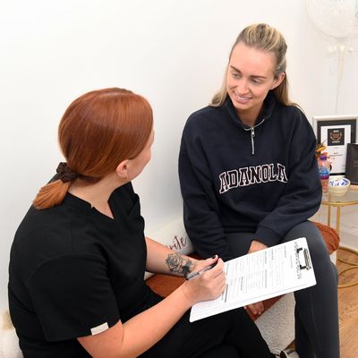 Two women engaged in a consultation, one holding a clipboard with a form.