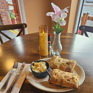 Table setting with focaccia bread, dip, a lit candle, and a flower in a vase.