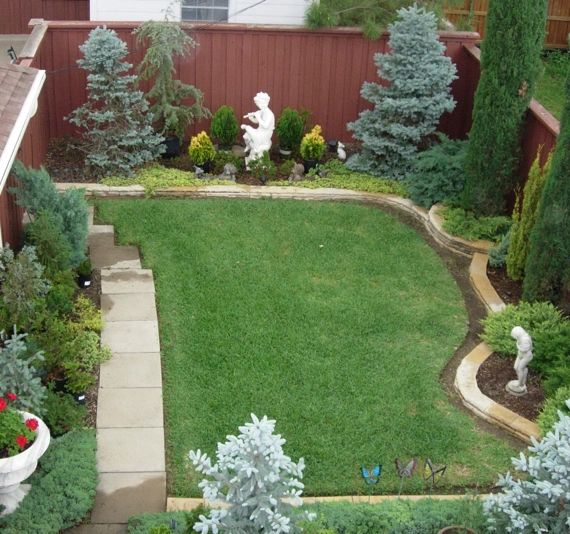 A well-maintained backyard with green grass and statues.