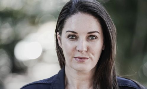 Confident woman with dark hair looking directly at the camera outdoors.