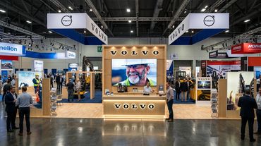 Volvo exhibition booth at a trade show with a large display and visitors.