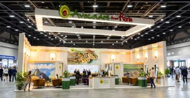 Exhibition booth showcasing Peru's avocado industry with visitors interacting.