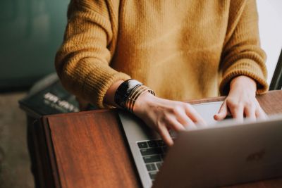 Person typing on a laptop at a wooden table.