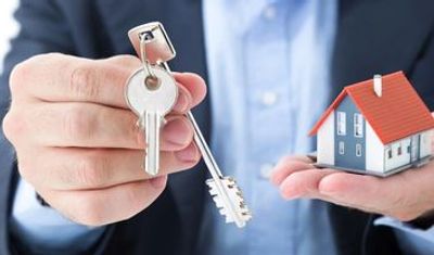 Two people shaking hands in front of large house, symbolizing real estate agreement or deal