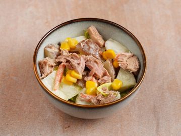 A bowl of salad with tuna, corn, potatoes, and carrots.