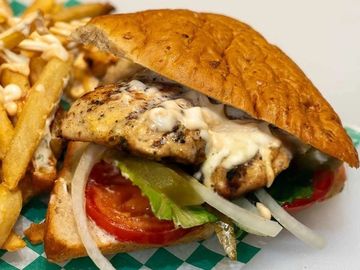 Grilled chicken sandwich with fresh veggies and fries on the side.