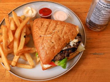 Grilled burger sandwich with fries and three dipping sauces.