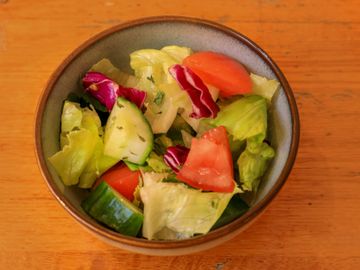 A bowl of fresh mixed vegetable salad with lettuce, tomato, and cucumber.