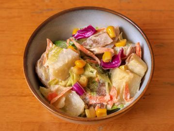 A colorful creamy salad with corn, carrots, and cabbage in a bowl.