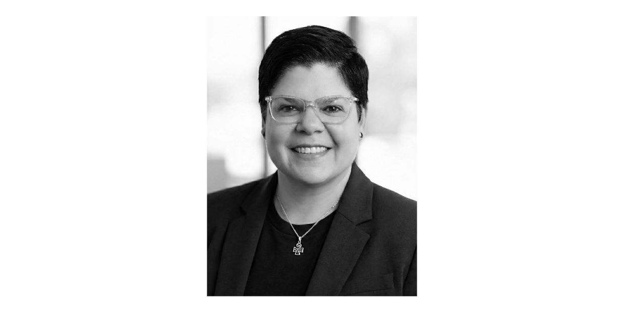 Portrait of a woman with long black hair and a warm brown top.