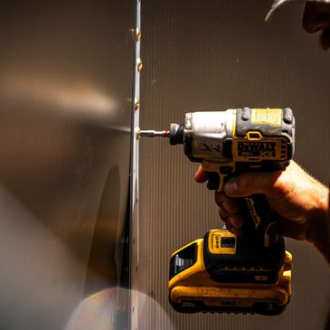 Person using a DeWalt power drill on a wall.