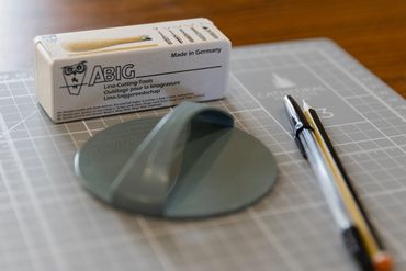 A sanding tool, pen, and packaging on a cutting mat.