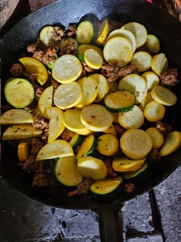 Sautéed yellow and green squash with ground meat in a cast iron pan.