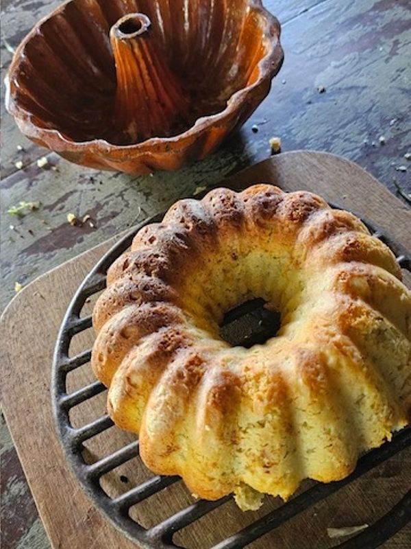 Golden-brown bundt cake fresh out of a vintage mold on a cooling rack.