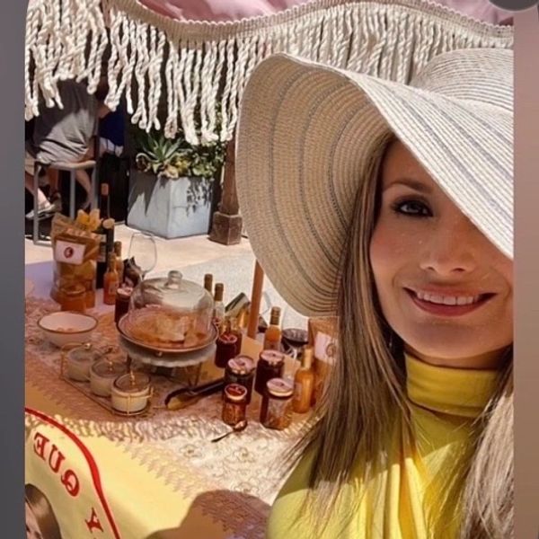 Woman in a large sunhat at a market stall with jars and bottles.