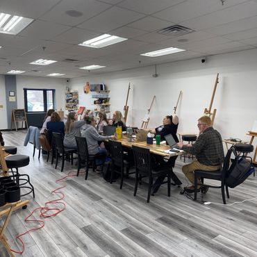 People working at a long table in an art studio.