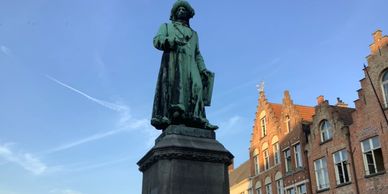 Statue of a man on a pedestal in front of historic buildings.