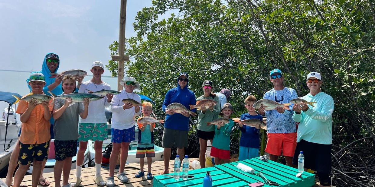 Group of people proudly holding their catch after fishing.