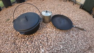 Cast iron cookware and a metal pot on gravel.