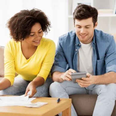 Two people working together, one using a calculator, the other reviewing papers.