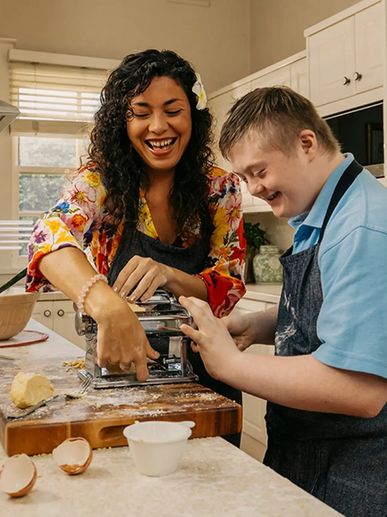 Two people happily making pasta together in a kitchen.