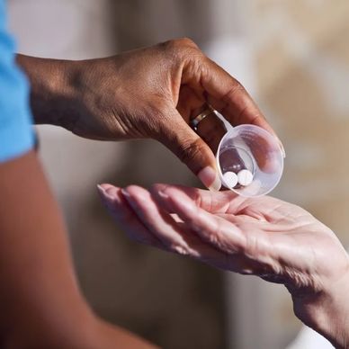 A person pouring pills from a cup into another's hand.
