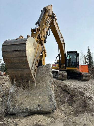Removing a large boulder with an excavator. Prep for a new build.