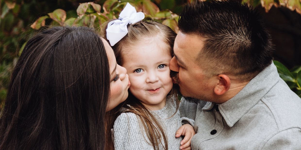 family photography of mom and dad kissing child