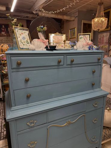 Blue dresser adorned with bunny figurines and framed art.