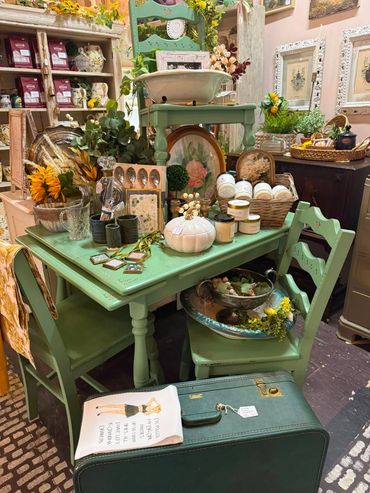 Vintage green table with décor and suitcase in a cozy shop.