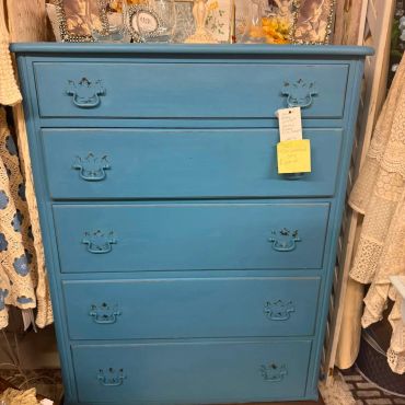 Vintage blue wooden chest of drawers with decorative handles.