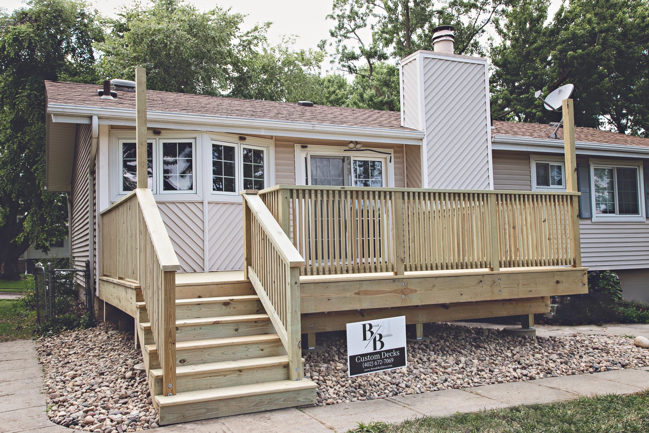 Wooden deck attached to a house with a chimney.