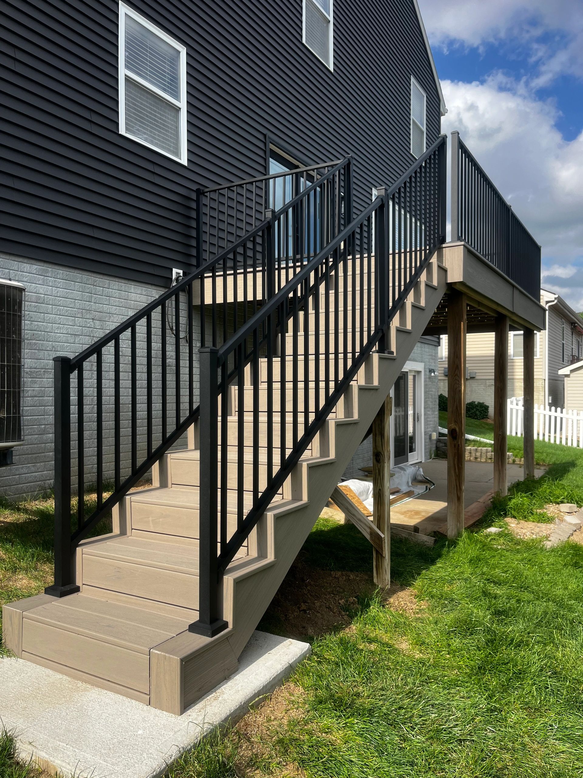 Outdoor staircase leading to a deck with black metal railings.