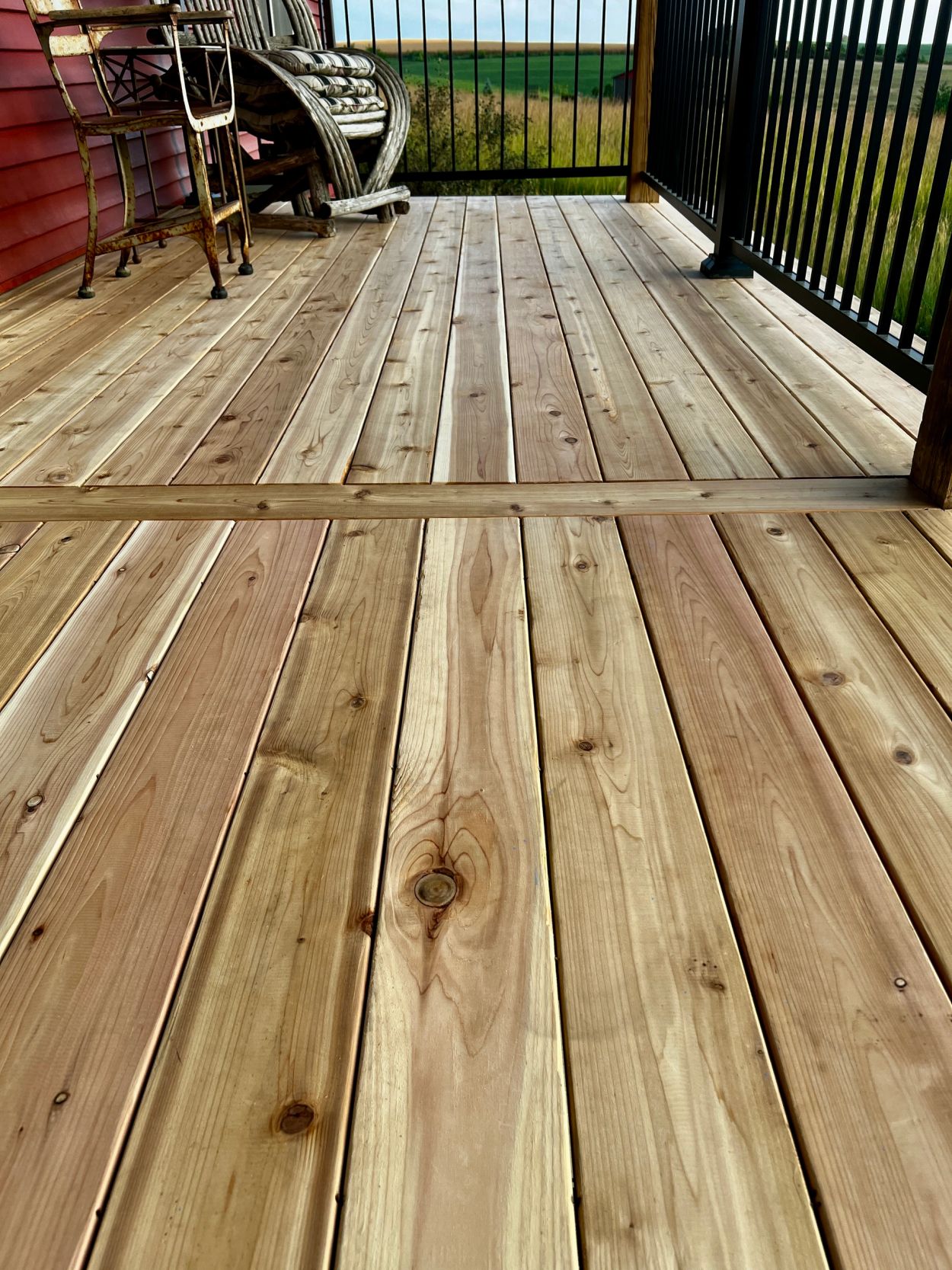 Freshly sanded wooden deck with metal railing and outdoor furniture.