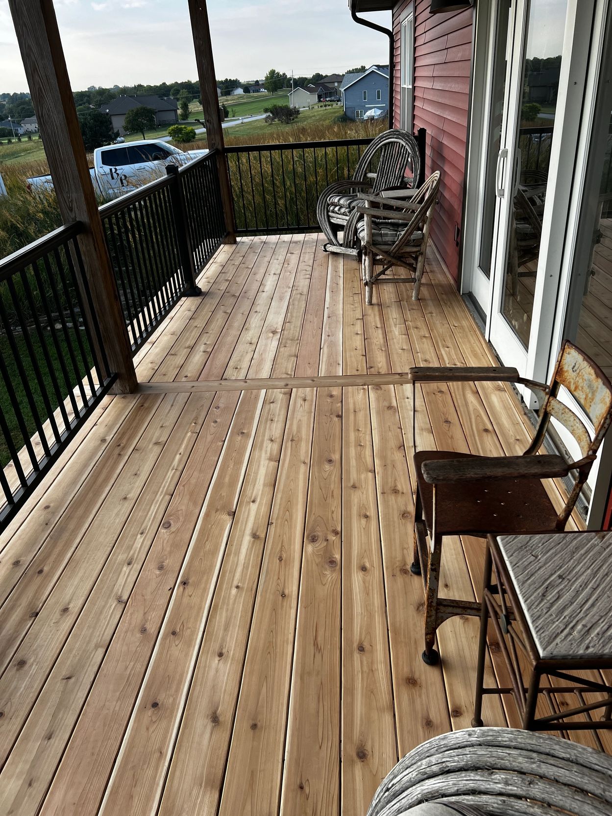 Wooden deck with chairs and metal railing.