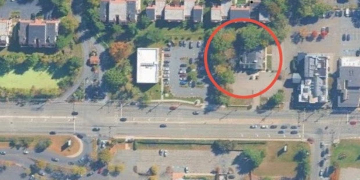 Aerial view of a neighborhood with a building circled in red among trees and parking lots.