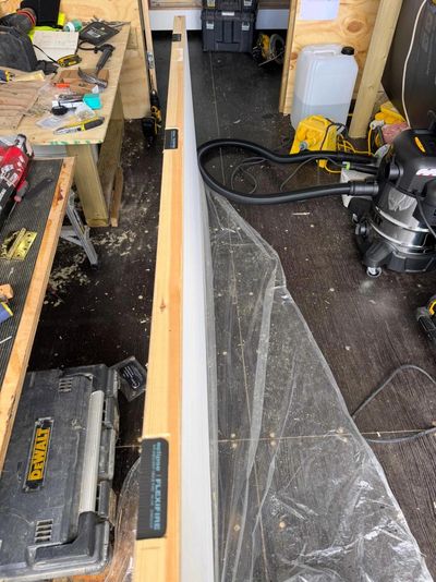 A carpentry workspace with tools and a wooden plank stretched with a string line.