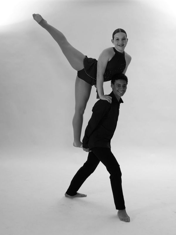 Dance partners performing a balancing pose in navy costumes.