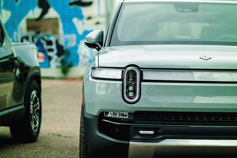 Rivian SUV, light green, sitting in parking lot.