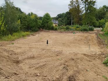 Przygotowany plac pod budowę w otoczeniu zieleni.