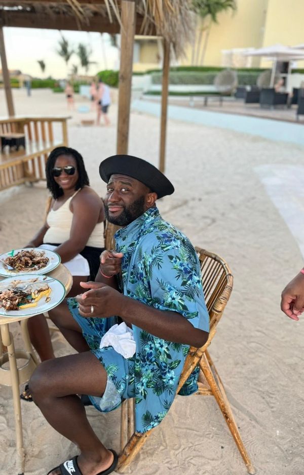 A couple sitting outside eating jerk chicken. 